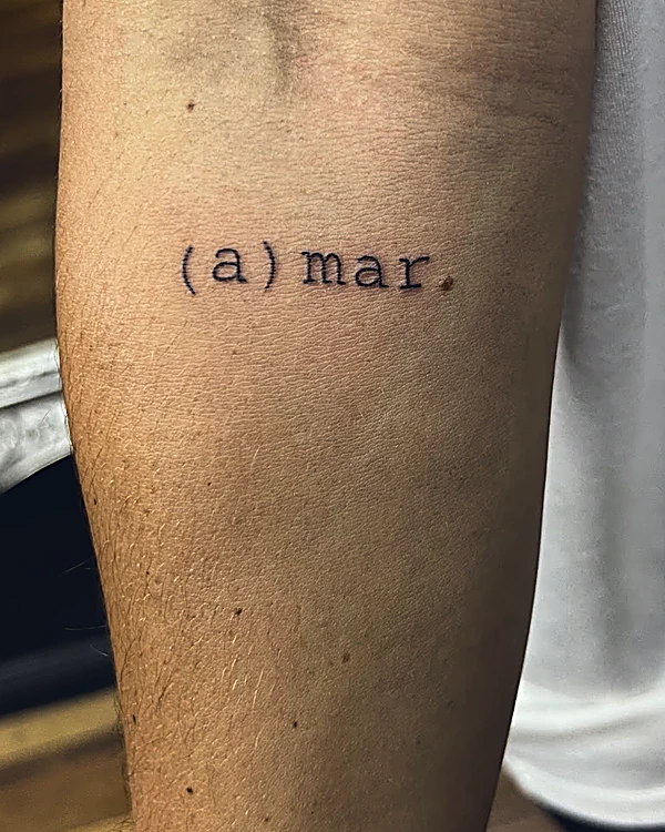 La palabra (a)mar. con letra de máquina de escribir, tatuada en el brazo